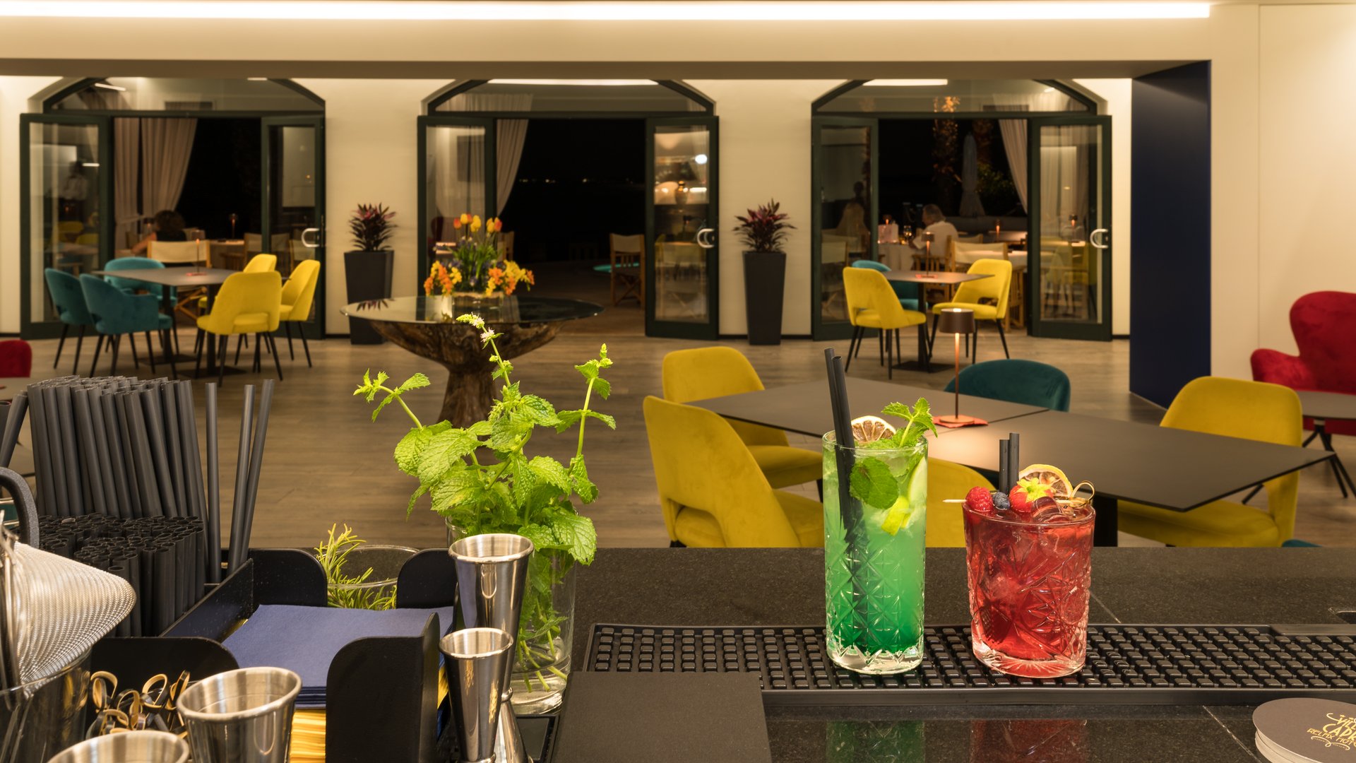 A laid-back holiday on Lake Garda at a 4-star hotel Bar with two cocktails and colorful chairs in a modern restaurant