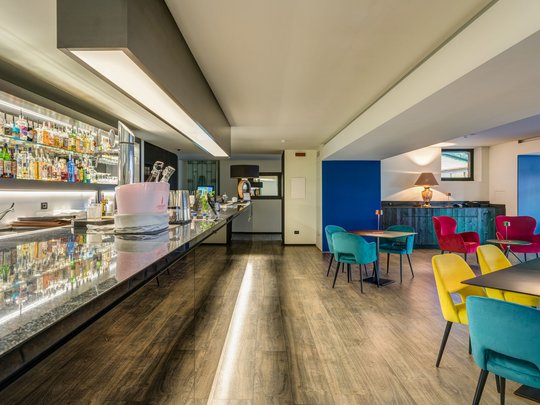 A laid-back holiday on Lake Garda at a 4-star hotel Modern cocktail bar interior with colorful chairs and illuminated counter