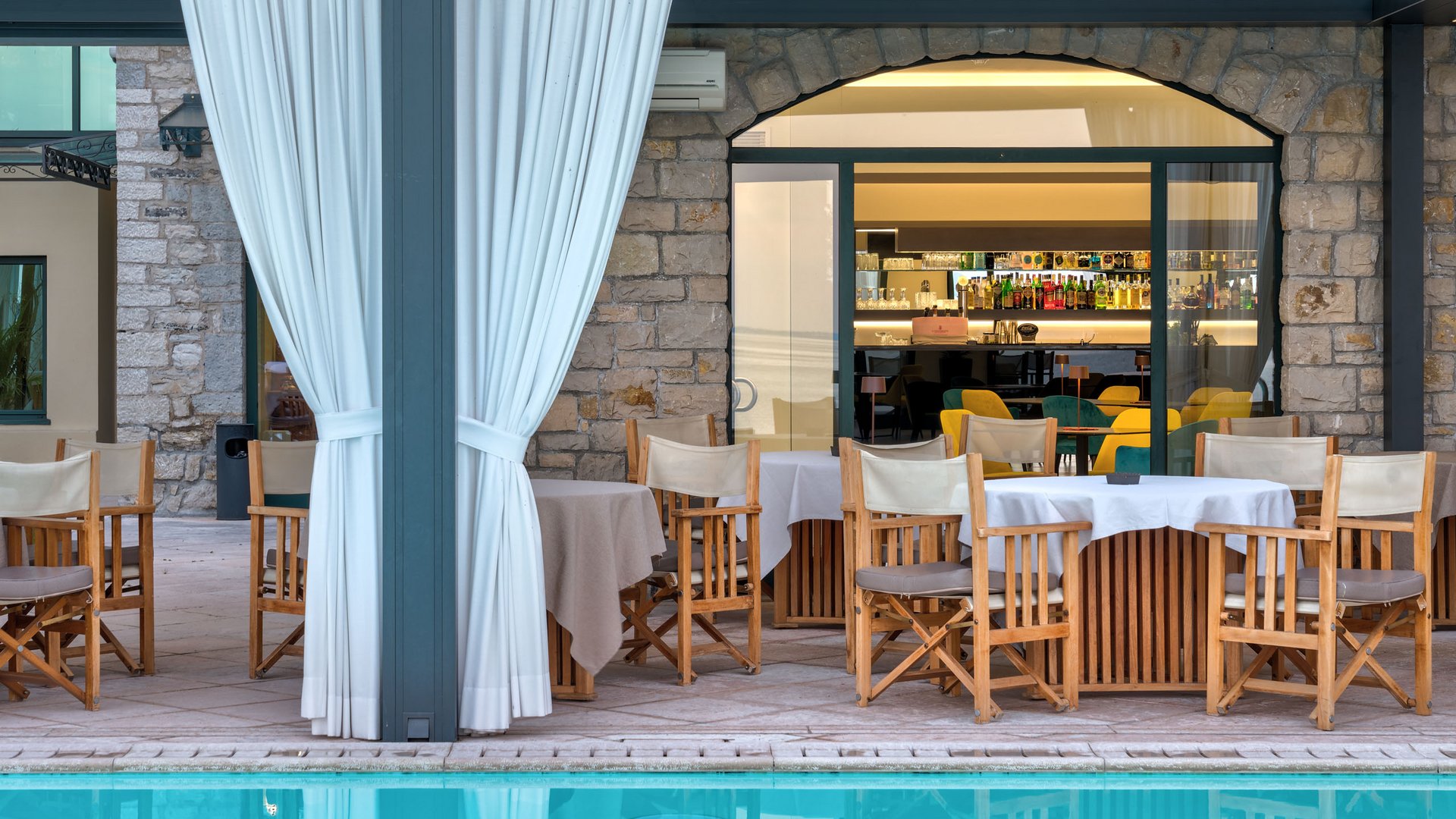 A laid-back holiday on Lake Garda at a 4-star hotel Outdoor restaurant with wooden chairs and tables beside a pool