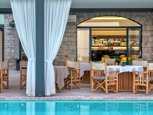 A laid-back holiday on Lake Garda at a 4-star hotel Outdoor restaurant with wooden chairs and tables beside a pool