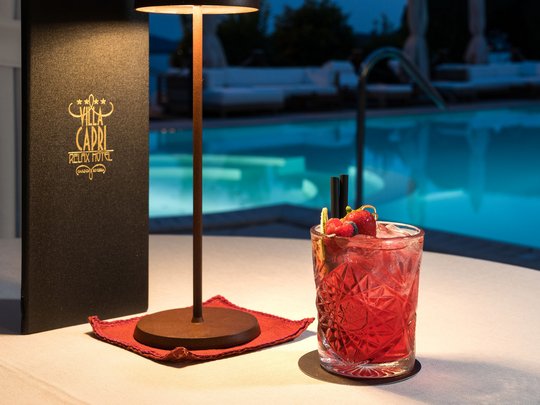 A laid-back holiday on Lake Garda at a 4-star hotel Red cocktail glass with fruit next to a lamp by the pool at Villa Capri hotel