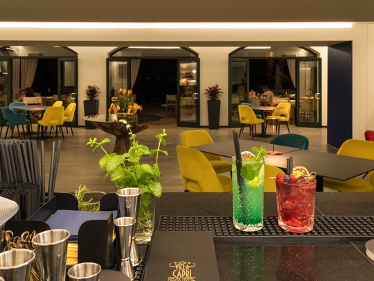 A laid-back holiday on Lake Garda at a 4-star hotel Bar with colorful chairs and two cocktails in a modern restaurant